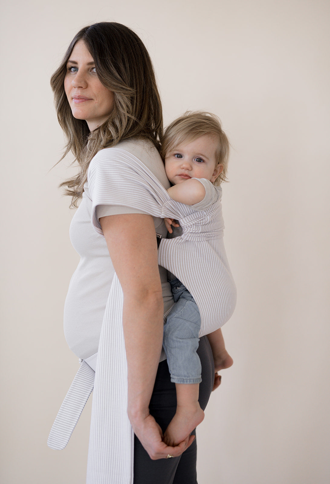 Pregnant female back carrying a baby in an Oatmeal Stripe Simple Wrap.