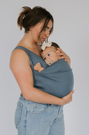 Side view of a female wearing a newborn in a Brook Soothe Shirt.