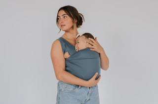 Female wearing a newborn in a Brook Soothe Shirt.