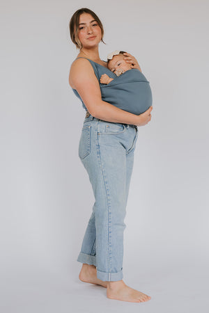 Full body view of a female wearing a newborn in a Brook Soothe Shirt.