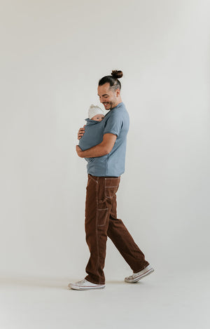 Male wearing a newborn in a Brook Dad Shirt.