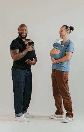 Two males wearing newborns in a black and a Brook Dad Shirt.