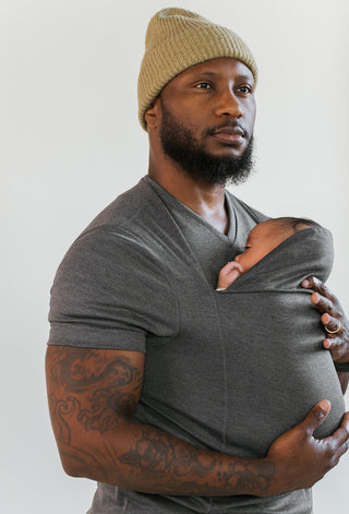 Male wearing a newborn in a gray Dad Shirt.