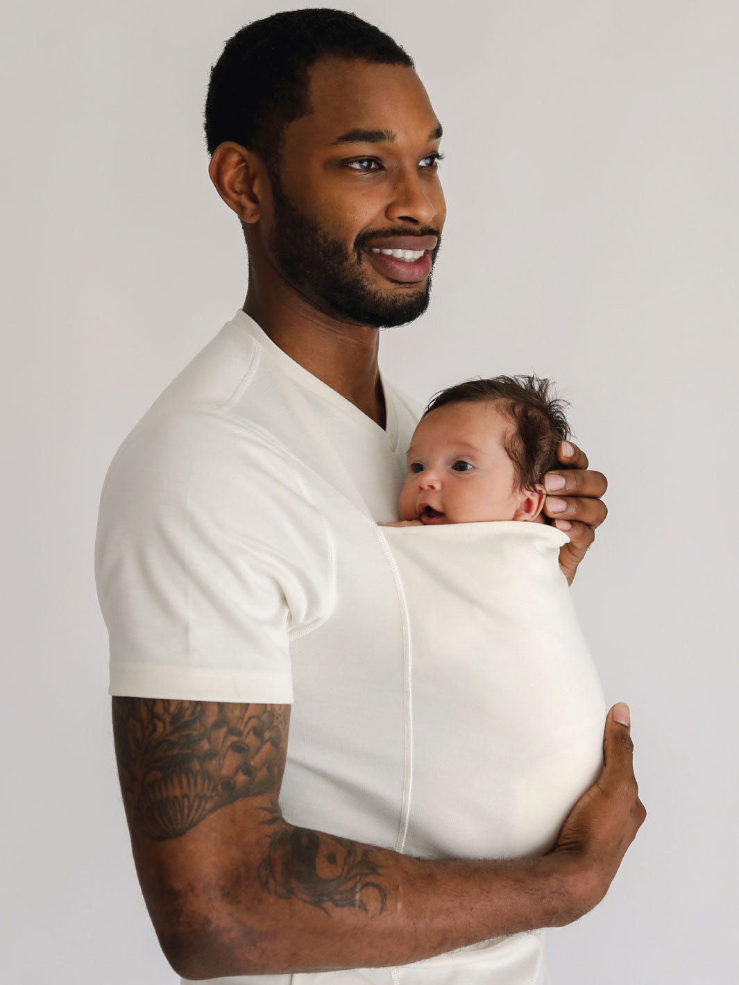 Male wearing a newborn in a Natural Dad Shirt.