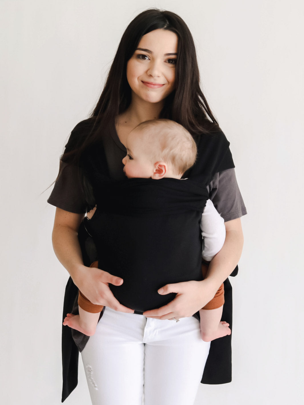 Female front carrying a baby in a black Simple Wrap.