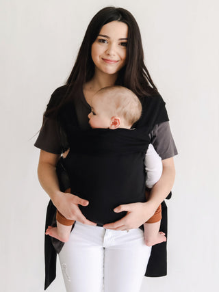 Front view of a female front carrying a baby in a black Simple Wrap.