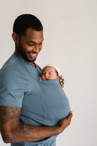 Male wearing a newborn in a Brook Dad Shirt.